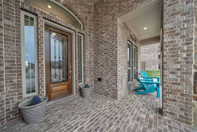 doorway to property with brick siding and covered porch