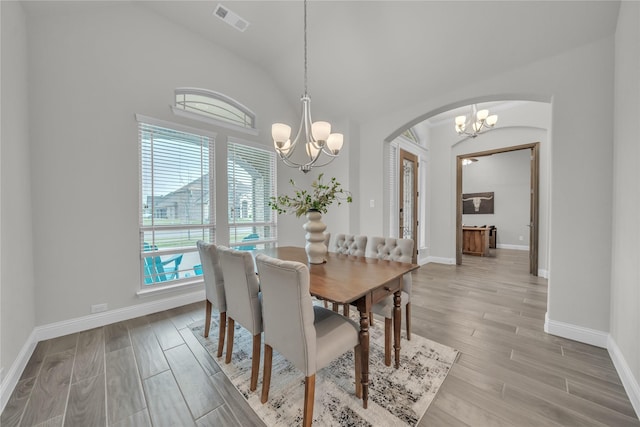 dining area with vaulted ceiling, visible vents, arched walkways, and a notable chandelier