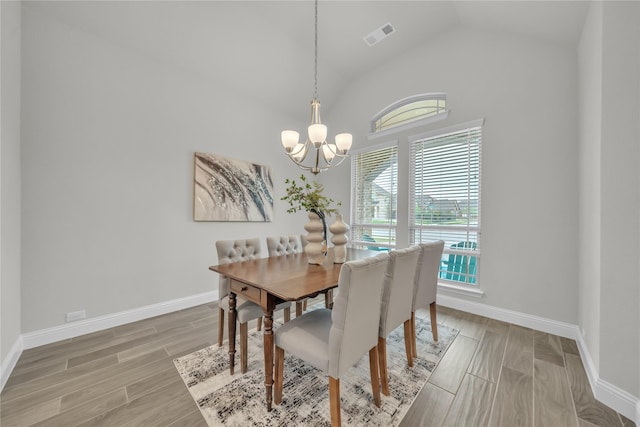 dining area with light wood-type flooring, vaulted ceiling, baseboards, visible vents, and a notable chandelier