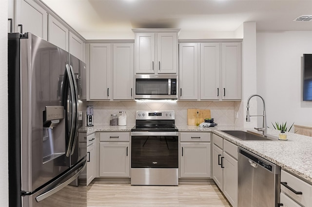 2728 Baneberry Ln, Mesquite, TX 75150 - kitchen featuring appliances with stainless steel finishes, a sink, decorative backsplash, and light wood-type flooring