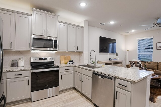 2728 Baneberry Ln, Mesquite, TX 75150 - kitchen with stainless steel appliances, a sink, a peninsula, decorative backsplash, and a ceiling fan