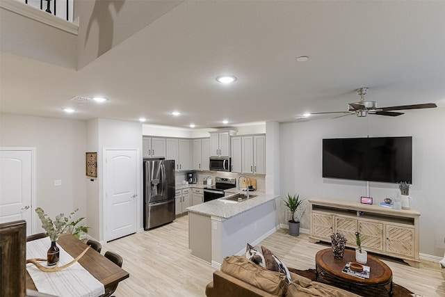 2728 Baneberry Ln, Mesquite, TX 75150 - kitchen with appliances with stainless steel finishes, a sink, baseboards, light wood-style flooring, and a peninsula