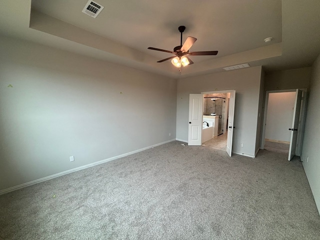 unfurnished bedroom featuring visible vents, baseboards, carpet, and a tray ceiling