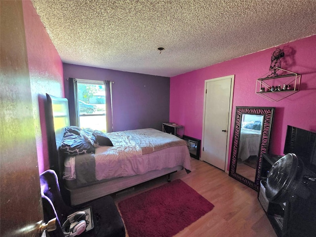 bedroom with a textured ceiling and wood finished floors