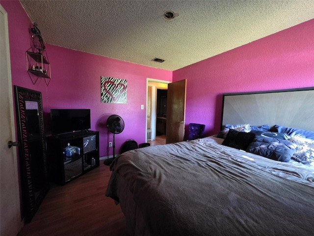 bedroom with a textured ceiling, visible vents, and wood finished floors