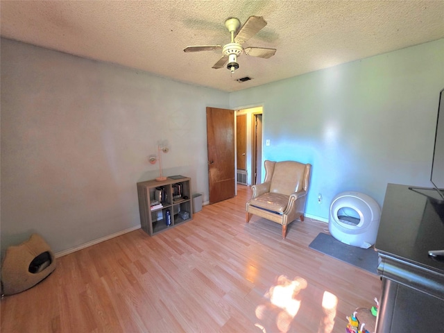 sitting room with a ceiling fan, baseboards, a textured ceiling, and wood finished floors
