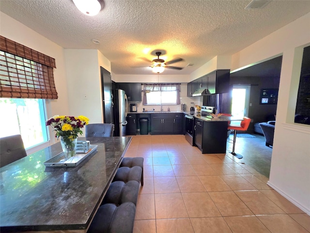 kitchen featuring light tile patterned floors, a kitchen breakfast bar, appliances with stainless steel finishes, and a textured ceiling