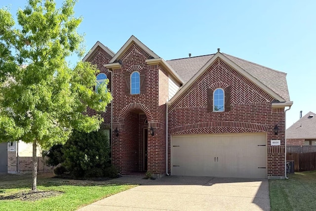 traditional-style house featuring a garage, fence, brick siding, a shingled roof, and driveway