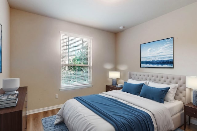 bedroom featuring baseboards, multiple windows, and wood finished floors
