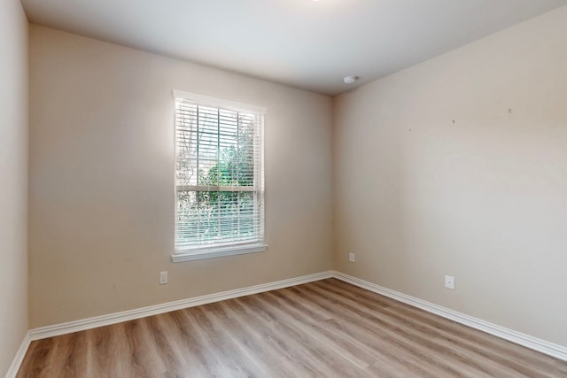 spare room featuring light wood-type flooring and baseboards