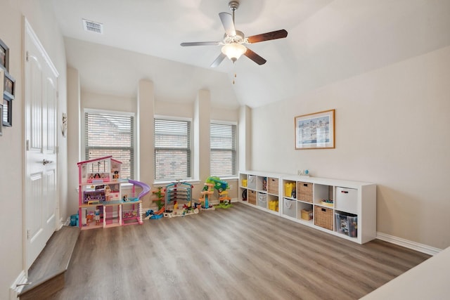 game room with a ceiling fan, vaulted ceiling, visible vents, wood finished floors, and baseboards