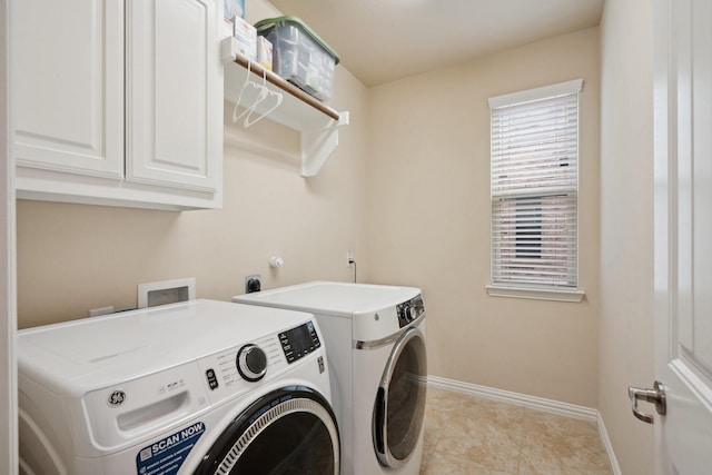 clothes washing area featuring separate washer and dryer, baseboards, and cabinet space