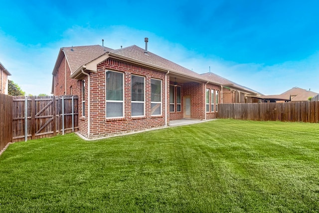 back of property featuring a yard, brick siding, a fenced backyard, and a patio area