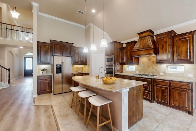kitchen with visible vents, light stone countertops, custom range hood, high vaulted ceiling, and stainless steel appliances