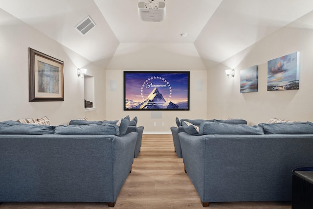 home theater featuring visible vents, light wood-style flooring, and lofted ceiling