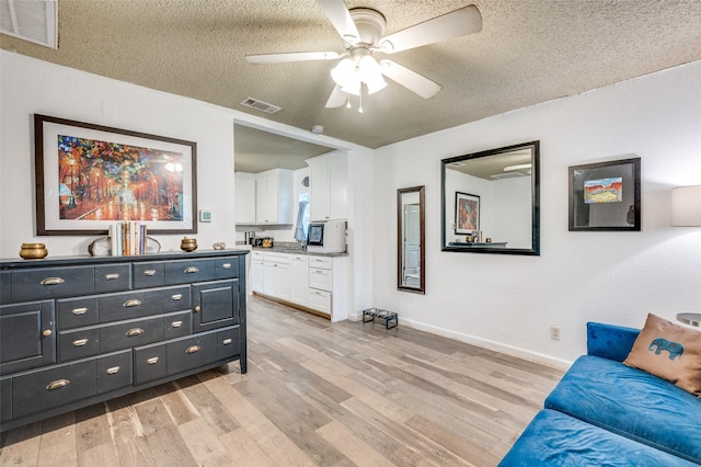 living area with a ceiling fan, visible vents, and light wood-type flooring