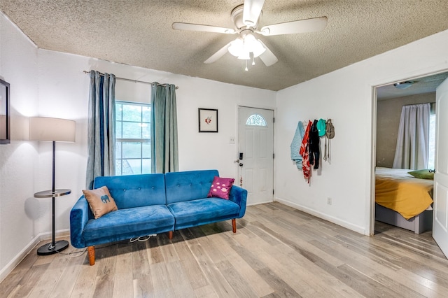 living room with a textured ceiling, baseboards, ceiling fan, and wood finished floors