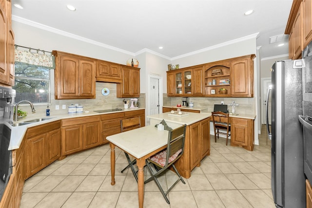 kitchen with a sink, decorative backsplash, light tile patterned flooring, brown cabinetry, and freestanding refrigerator