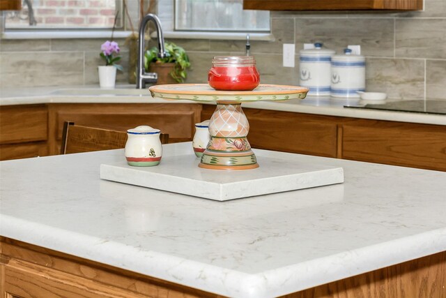 interior details with brown cabinetry, backsplash, light countertops, and a sink