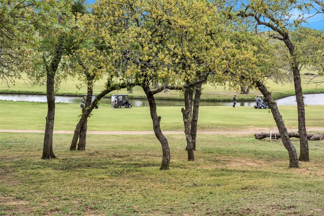 surrounding community with a water view and a lawn