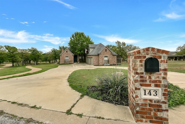 view of front of house with brick siding, a front lawn, and driveway