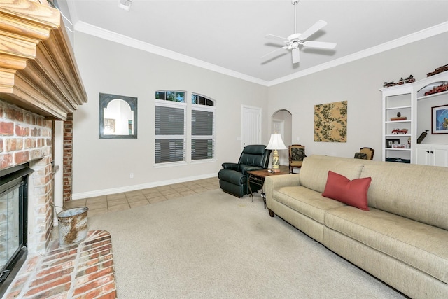 living room with tile patterned floors, ceiling fan, carpet flooring, a brick fireplace, and crown molding