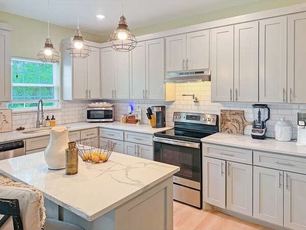 100 Winchester Cir, Gun Barrel City, TX 75156 - kitchen with a kitchen bar, under cabinet range hood, decorative backsplash, a sink, and appliances with stainless steel finishes