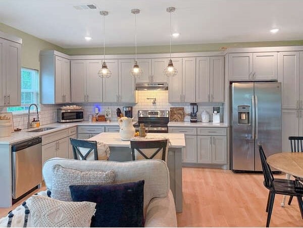 100 Winchester Cir, Gun Barrel City, TX 75156 - kitchen with light countertops, light wood finished floors, appliances with stainless steel finishes, under cabinet range hood, and a sink
