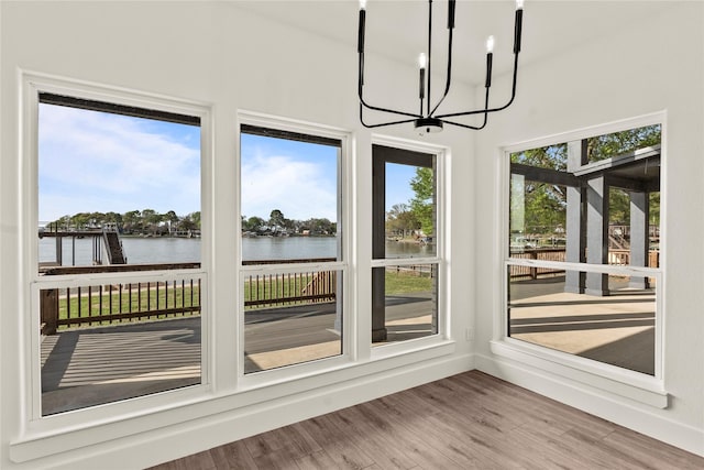 unfurnished sunroom with a water view and a chandelier