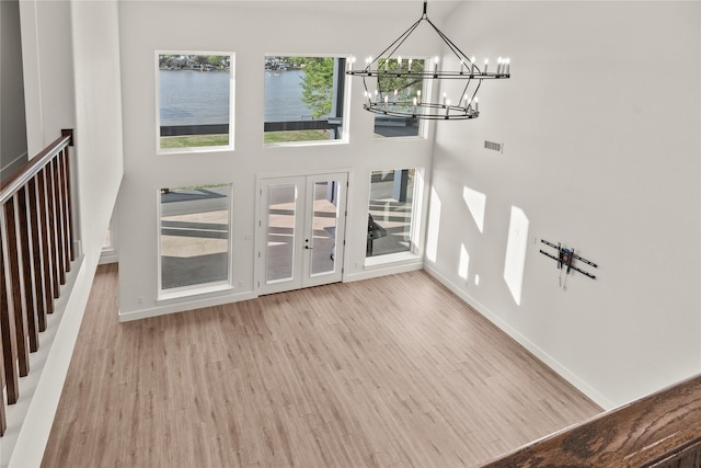 foyer entrance featuring visible vents, a chandelier, wood finished floors, a high ceiling, and french doors