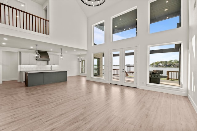 unfurnished living room with recessed lighting, french doors, baseboards, a sink, and light wood finished floors