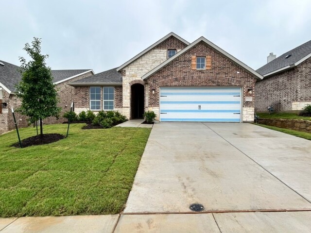 view of front of property with a front lawn, stone siding, brick siding, an attached garage, and driveway