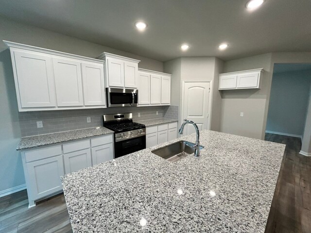kitchen featuring white cabinets, baseboards, appliances with stainless steel finishes, and a sink