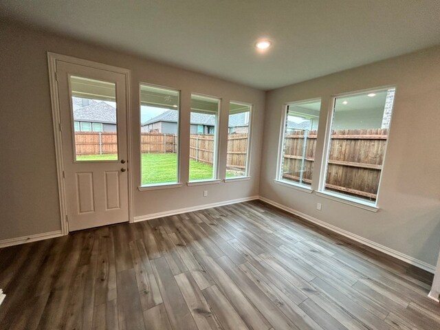 doorway with dark wood-style flooring, baseboards, and plenty of natural light