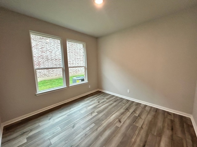unfurnished room featuring baseboards and dark wood-style floors