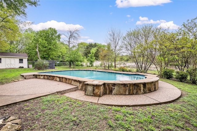 view of swimming pool featuring a yard, fence, an outdoor structure, and a patio area