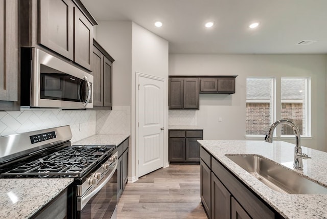 3523 Columbus St, Gainesville, TX 76240 - kitchen with appliances with stainless steel finishes, a sink, light wood-style flooring, dark brown cabinets, and recessed lighting