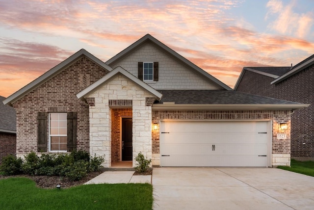 3523 Columbus St, Gainesville, TX 76240 - french country inspired facade featuring driveway, an attached garage, brick siding, stone siding, and a shingled roof