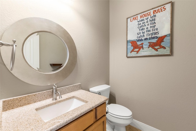 bathroom featuring a textured wall, toilet, and vanity
