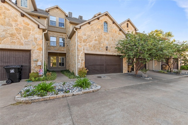 townhome / multi-family property featuring stone siding, a garage, and concrete driveway