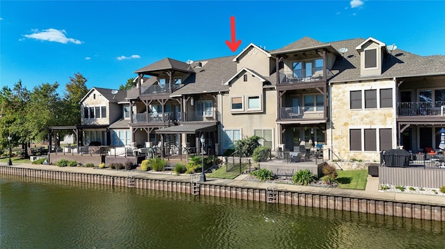 rear view of property with stucco siding, a patio, stone siding, a residential view, and a water view