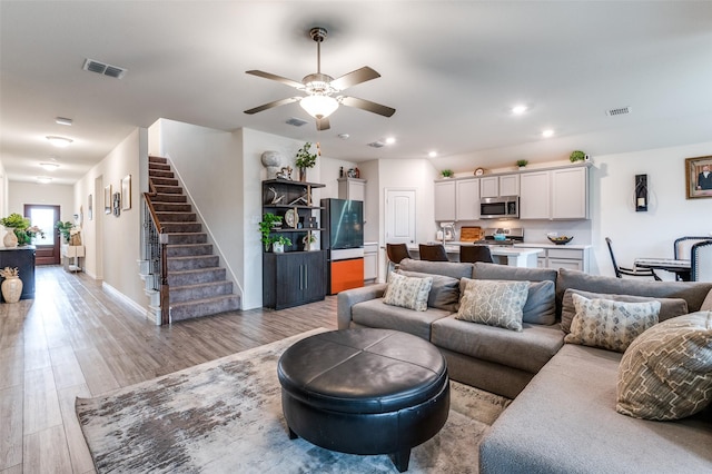 799 Bayberry Ln, Princeton, TX 75407 - living room with visible vents, light wood-style floors, ceiling fan, and stairway