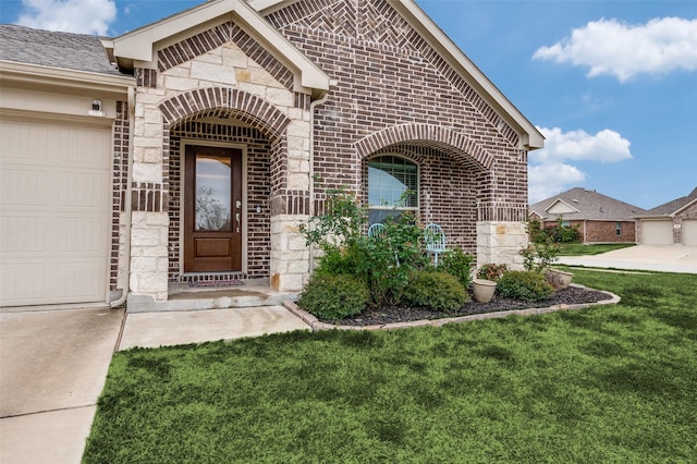799 Bayberry Ln, Princeton, TX 75407 - doorway to property featuring a garage, stone siding, a lawn, and brick siding