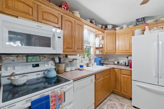 kitchen with a sink, a textured ceiling, white appliances, light countertops, and light tile patterned flooring