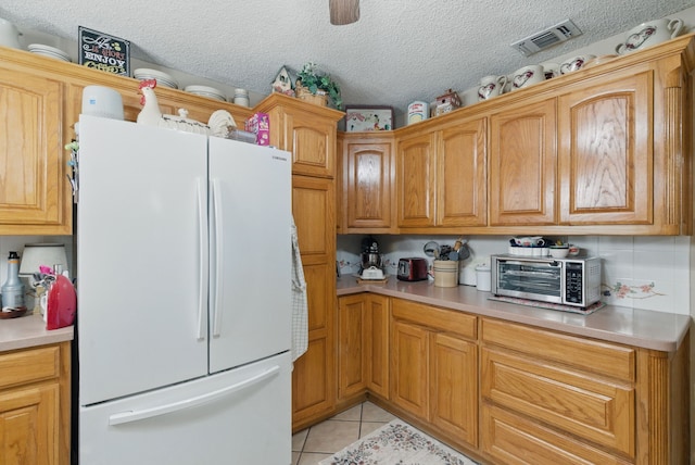 kitchen with freestanding refrigerator, light countertops, light tile patterned floors, and visible vents