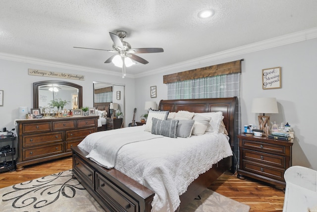 bedroom with a ceiling fan, ornamental molding, light wood-type flooring, and a textured ceiling