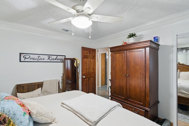 bedroom featuring ornamental molding, a textured ceiling, a ceiling fan, and visible vents