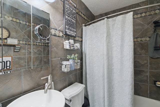 full bathroom with tile walls, a textured ceiling, toilet, and a sink