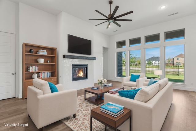 living room featuring a tiled fireplace, wood finished floors, visible vents, ceiling fan, and recessed lighting