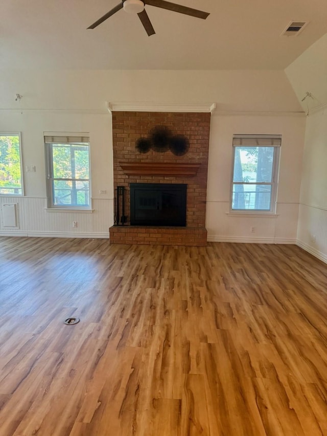 316 Oak Ln, Tool, TX 75143 - unfurnished living room with plenty of natural light, a brick fireplace, wood finished floors, vaulted ceiling, and a wainscoted wall